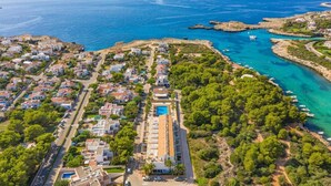 Vista aérea de una zona residencial costera con casas, una piscina y aguas azules cristalinas.