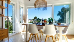 A dining area with a table set for four, chairs, a hanging light fixture, and a view of the outdoors. - Villa 'Casa Mar Y' with Sea View, Wi-Fi and Air Conditioning (Moraira)