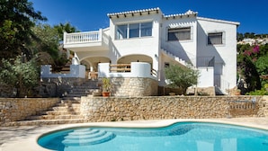 A two-story house with a stone retaining wall, a swimming pool, and a balcony. - Villa 'Casa Mar Y' with Sea View, Wi-Fi and Air Conditioning (Moraira)