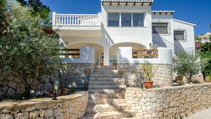 A white building with stone steps leading to a balcony, surrounded by greenery. - Villa 'Casa Mar Y' with Sea View, Wi-Fi and Air Conditioning (Moraira)