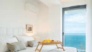 Ein Schlafzimmer mit einem Bett, einem Nachttisch mit einem Tablett Croissants, einem Glas Orangensaft und einem gerahmten Bild an der Wand.