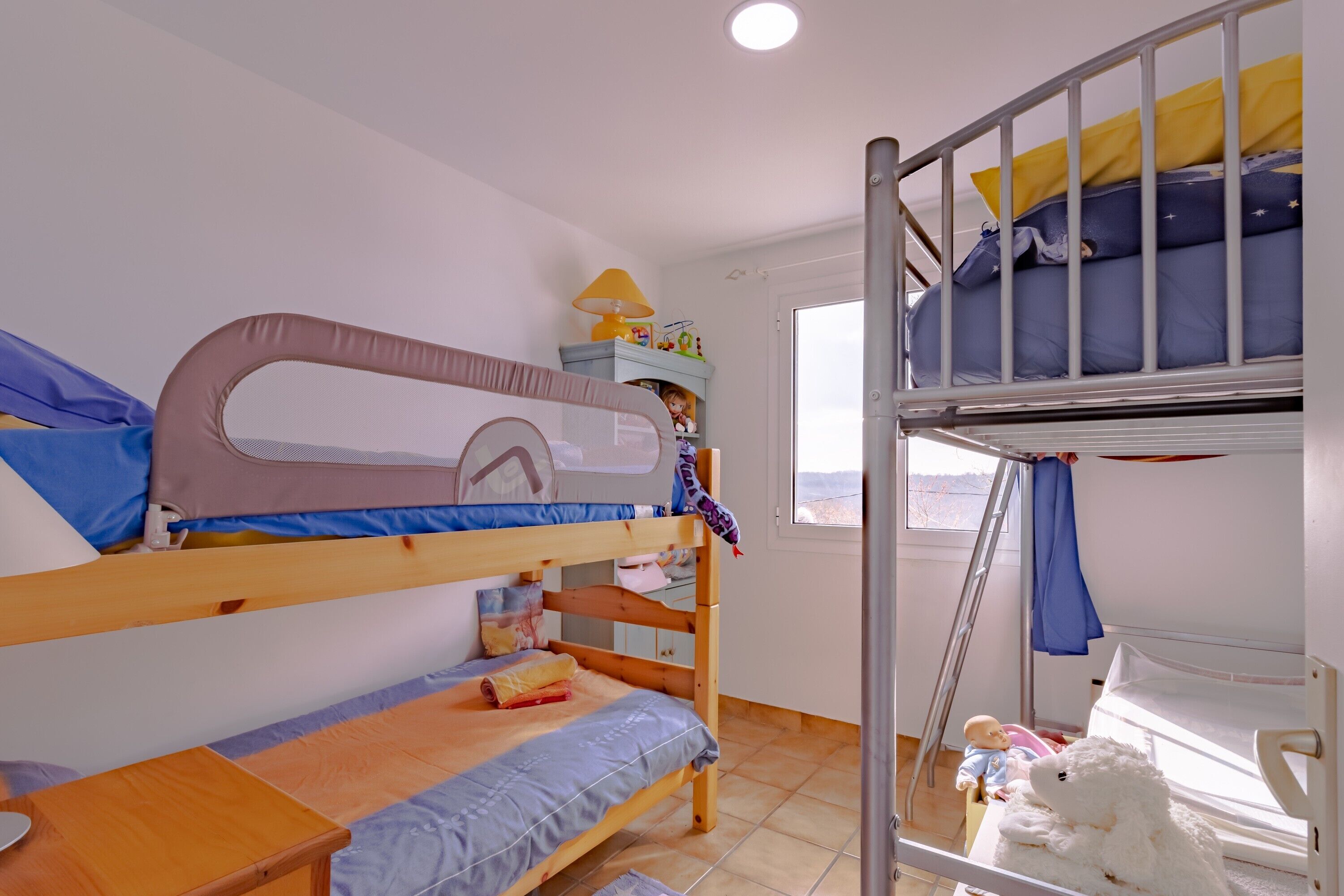 A bunk bed room with a window, a small table, and a toy on the lower bunk.