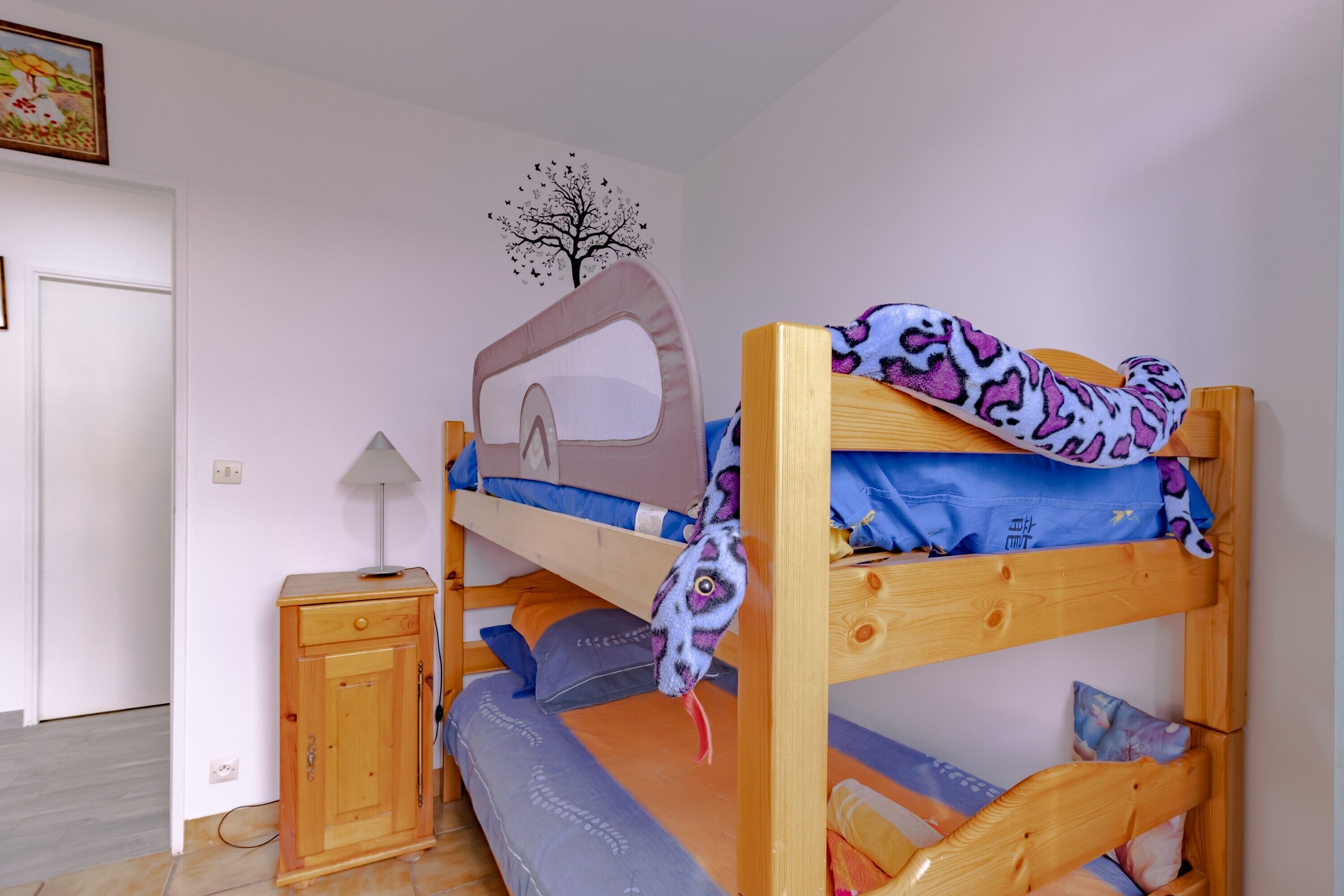 A bunk bed with a headboard, a bedside table, and a wall decoration.