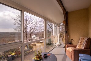 Une pièce avec de grandes fenêtres, un canapé, une petite table et une chaise.