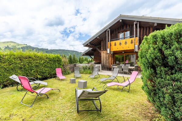 Un bâtiment en bois avec une enseigne jaune, des tables et des chaises à l’extérieur, et une pelouse bien entretenue.