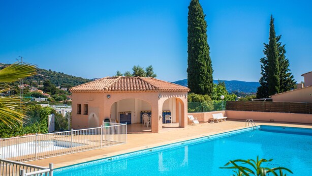 A swimming pool with a sun terrace, a small building with arches, and tall trees in the background. - Holiday Home 'Maison De Gathen' with Sea View, Shared Pool and Air Conditioning (Cavalaire-sur-Mer)