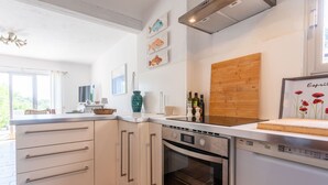 A modern kitchen with white cabinets, a built-in oven, and a dishwasher. - Holiday Home 'Maison De Gathen' with Sea View, Shared Pool and Air Conditioning (Cavalaire-sur-Mer)