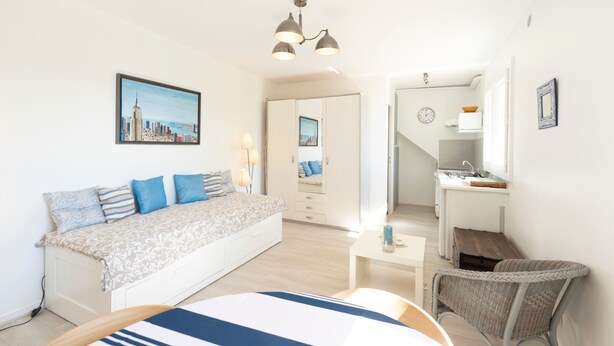 Una camera da letto moderna con un letto, comodini, una sedia, un quadro e angolo cottura.