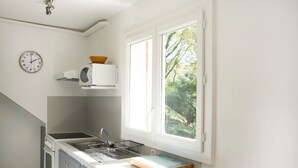 Una cucina con lavello, orologio e finestra che si affaccia sul verde.