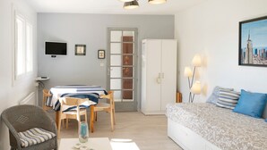 Una camera con un letto, una sedia, un tavolo, una TV, un armadio e una porta.