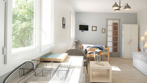 Una cucina moderna con lavastoviglie, zona pranzo con tavolo e sedie, divano e televisore appeso al muro.