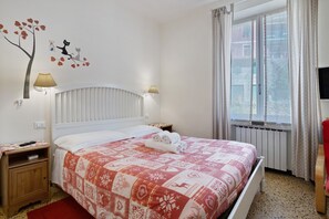 A bedroom with a bed, nightstands, a window, and a wall decoration.