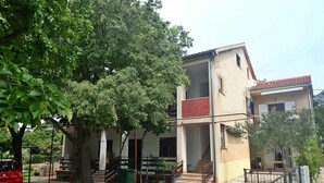 A two-story building with a red-tiled roof, a balcony, and a staircase leading to the upper floor.