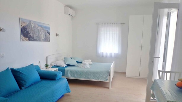 A bedroom with a bed, a sofa, a desk, and a wardrobe.