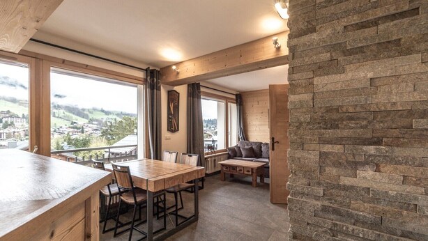 Una habitación amplia con una mesa de comedor de madera, un sofá y una pared decorativa de piedra.