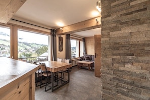 Une pièce spacieuse avec une table à manger en bois, un canapé et un mur décoratif en pierre.
