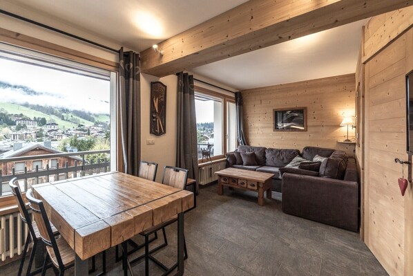 Un intérieur en bois avec une table à manger, un canapé et une vue sur la ville.