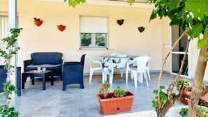 An outdoor patio area with a table and chairs, a sofa, and potted plants. - Villa surrounded in nature (Isola di Capo Rizzuto)