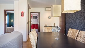 A modern dining area with a dark wooden table, wicker chairs, and a hanging light fixture. - 'Denia Sur' Apartment with Mountain Views, Wi-Fi, and Air Conditioning (La Xara)