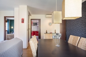 A modern dining area with a dark wooden table, wicker chairs, and a hanging light fixture.