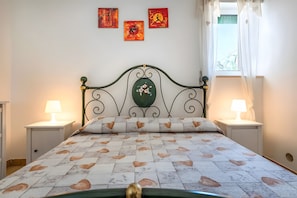 A bed with a patterned bedspread, two bedside lamps, and artwork on the wall. - Apartment 'Margherita' with Shared Pool, Wi-Fi and Air Conditioning (Ceglie Messapica)