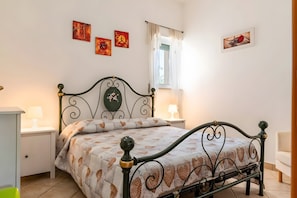 Un dormitorio ordenado con cama, mesitas de noche y decoración en la pared.