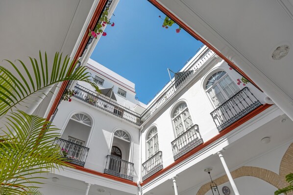 A white building with balconies, arched windows, and a clear blue sky.