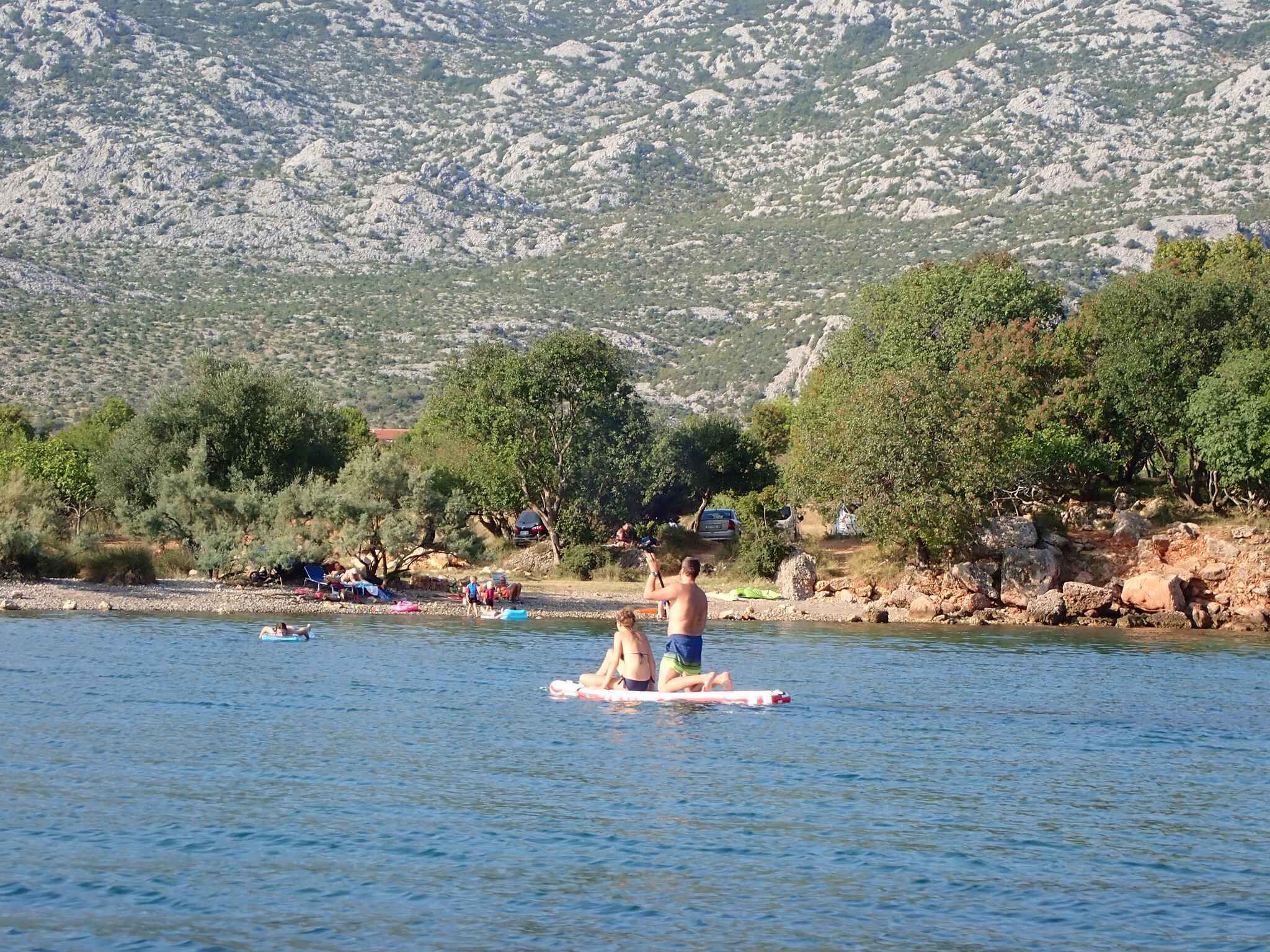 A lake with people on paddleboards, surrounded by trees and rocky hills.