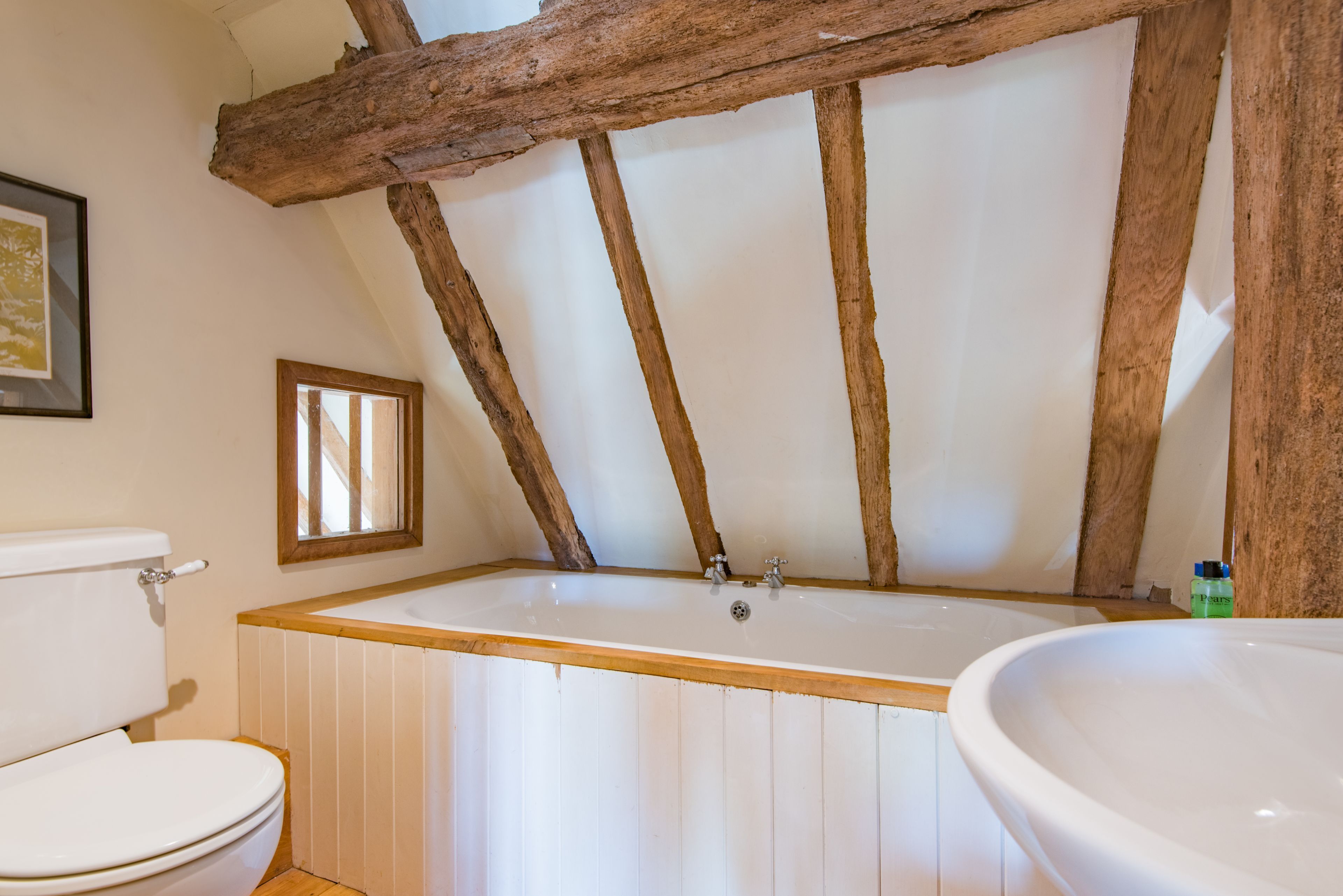 Une salle de bain avec un plafond en bois, une baignoire et un lavabo.