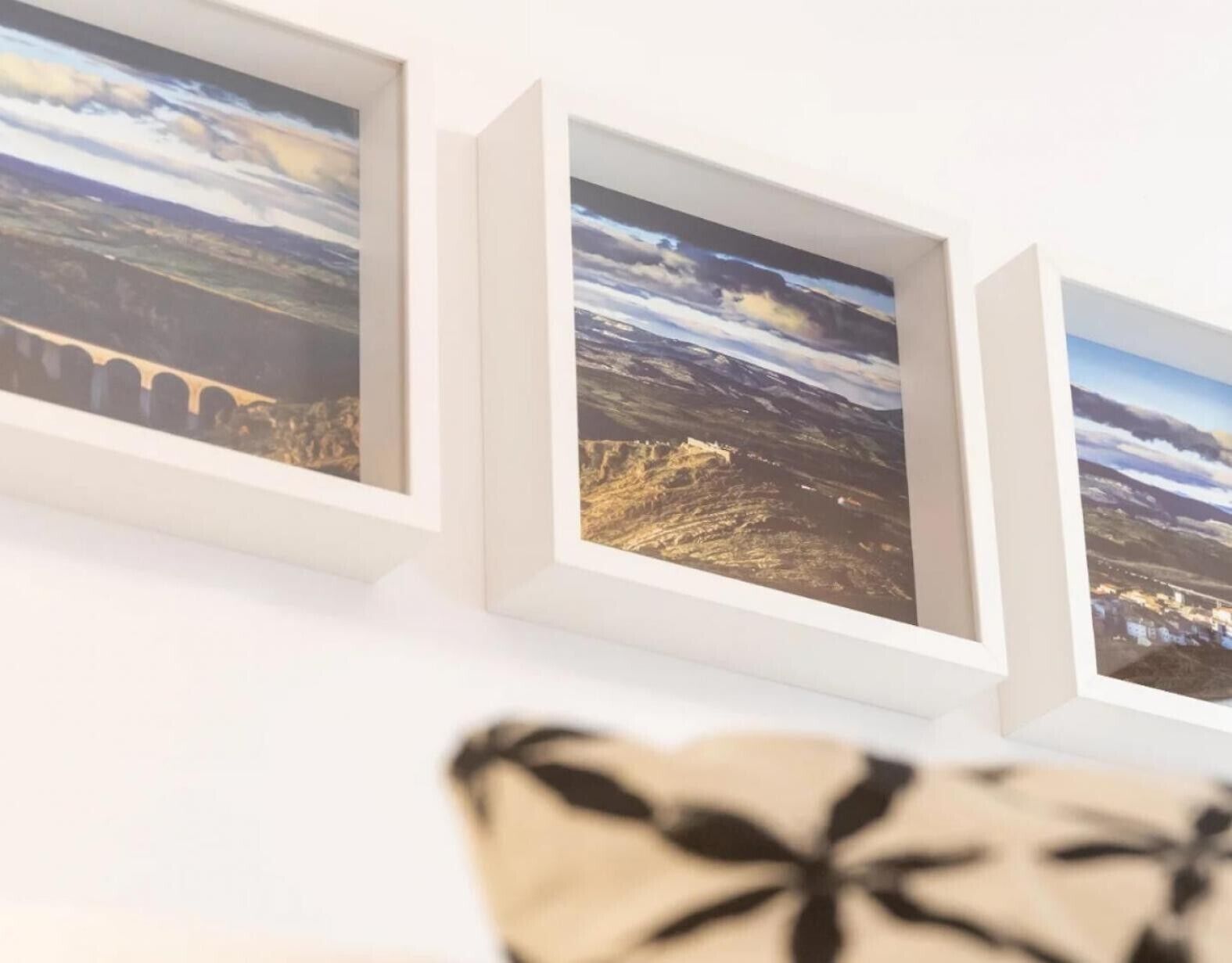 Drie ingelijste landschapsprenten aan een muur.