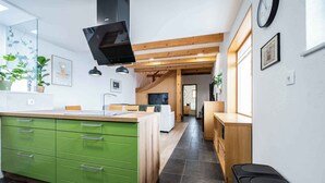 A modern kitchen with green cabinets, a central island, and a wooden ceiling.