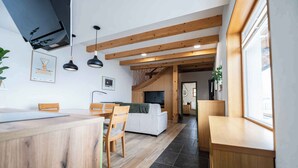 A modern kitchen with wooden beams, a dining area with a white sofa, and a view of the living room.