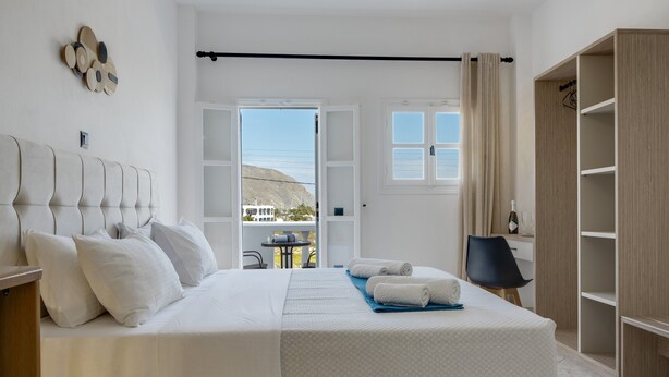 A bedroom with a bed, a wardrobe, a desk, and a view of the outside. - St George Sea View Double Room – Private Jacuzzi with Sea View (Santorini)