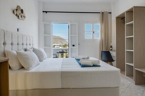 A bedroom with a bed, a wardrobe, a desk, and a view of the outside. - St George Sea View Double Room – Private Jacuzzi with Sea View (Santorini)