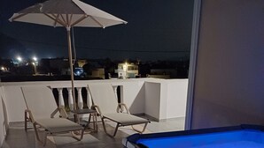 A rooftop terrace with a hot tub, lounge chairs, and an umbrella. - St George Sea View Double Room – Private Jacuzzi with Sea View (Santorini)