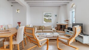 A living room with a sofa, chairs, a coffee table, a TV, and a fireplace. - Holiday Home 'Modern New Tinos' with Sea View, Private Terrace and Wi-Fi (Tinos)