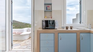 A kitchen with a microwave, cabinets, and a window. - Holiday Home 'Modern New Tinos' with Sea View, Private Terrace and Wi-Fi (Tinos)