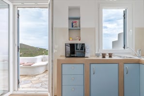 A kitchen with a microwave, cabinets, and a window.