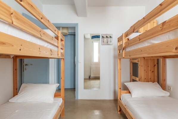 A room with bunk beds, a door, a mirror, and a wall-mounted light fixture.