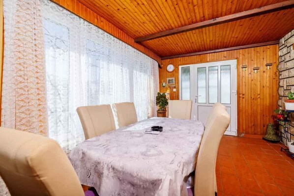 A dining area with a table set for four, wooden ceiling, and a door with glass panels.