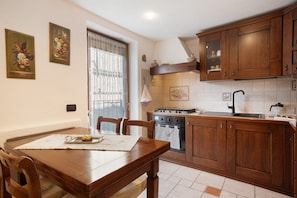 A kitchen with wooden cabinets, a stove, and a dining table with chairs.