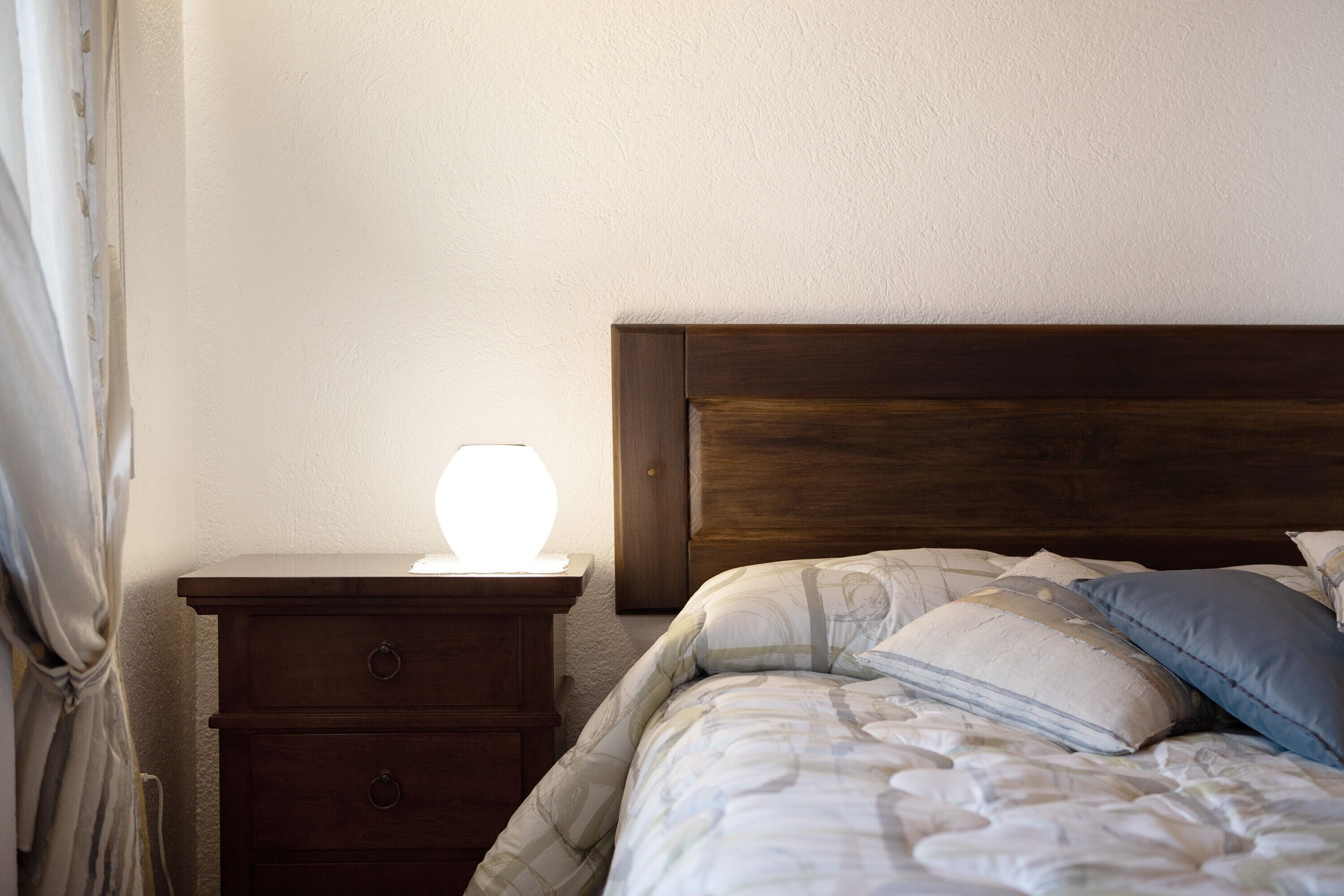 Une chambre à coucher avec une tête de lit en bois, une table de chevet avec une lampe et un lit avec des oreillers.