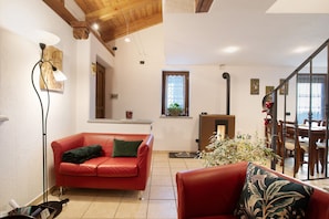 A living room with a red sofa, a floor lamp, a fireplace, and a dining area with wooden furniture.