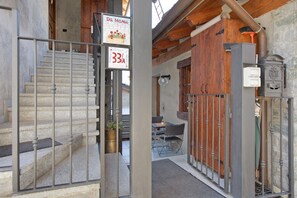 A staircase leading to a room with a wooden door, a sign with a price, and a small table with chairs.