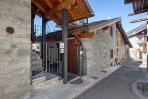 A stone building with a wooden staircase, a metal gate, and a sign indicating a restaurant.