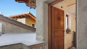 A wooden door leading to a room with a tiled floor, a small plant on a shelf, and a stone wall. - Apartment 'Manu - Blavy Nus' with Mountain View, Private Terrace and Wi-Fi (Blavy)