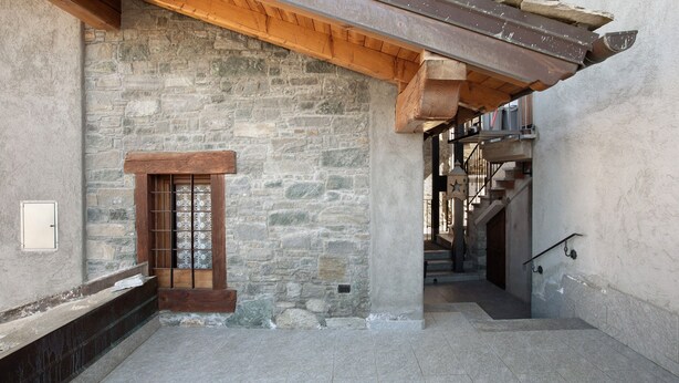 A stone-walled corridor with a wooden door, a staircase, and a metal railing. - Apartment 'Manu - Blavy Nus' with Mountain View, Private Terrace and Wi-Fi (Blavy)