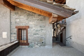 A stone-walled corridor with a wooden door, a staircase, and a metal railing. - Apartment 'Manu - Blavy Nus' with Mountain View, Private Terrace and Wi-Fi (Blavy)