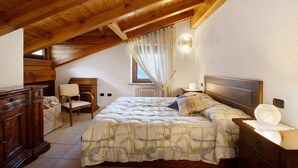 A bedroom with a wooden ceiling, a bed with a patterned bedspread, a nightstand, a chair, and a dresser. - Apartment 'Manu - Blavy Nus' with Mountain View, Private Terrace and Wi-Fi (Blavy)