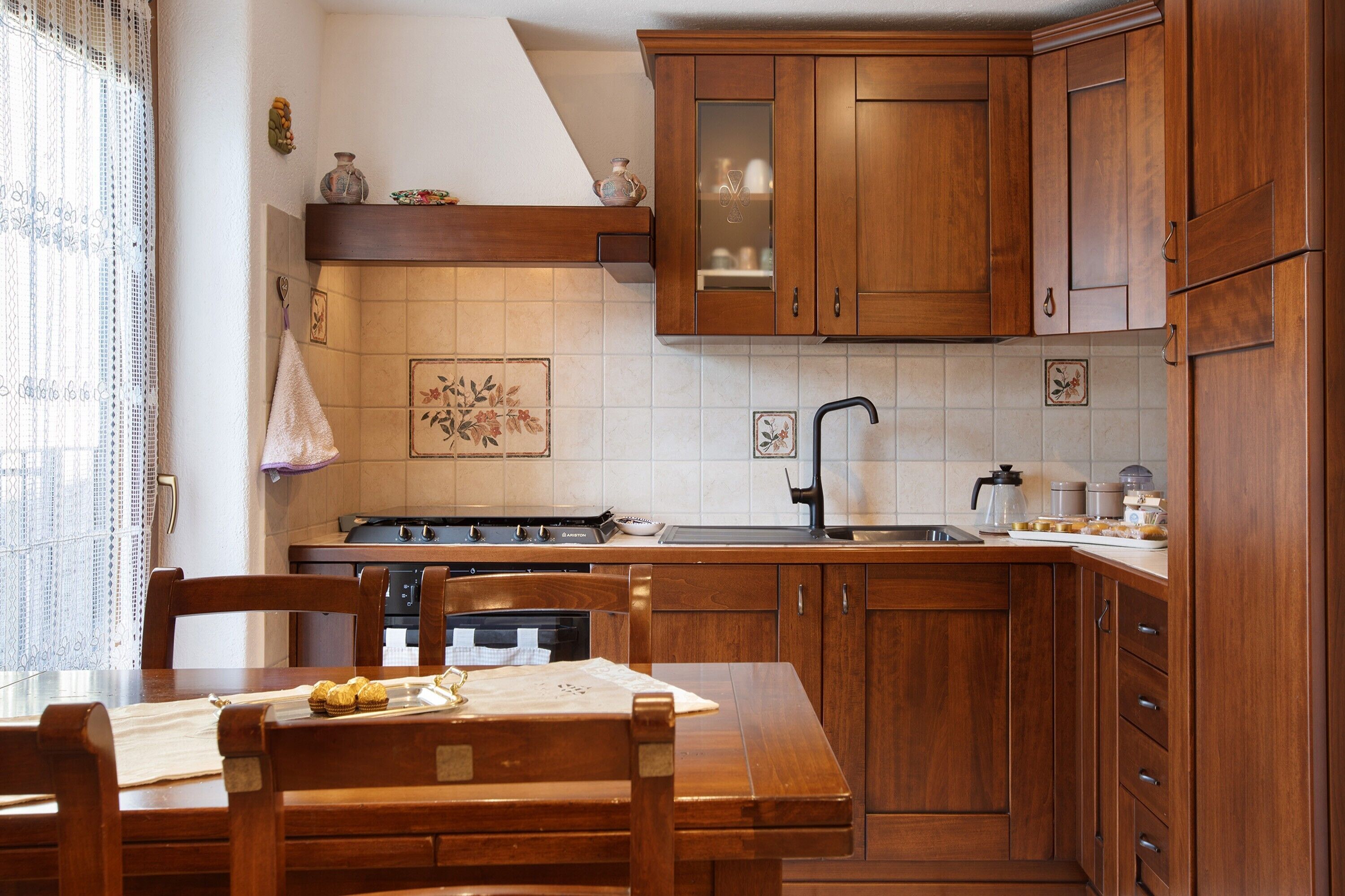 A kitchen with wooden cabinets, a stove, and a dining table with chairs.